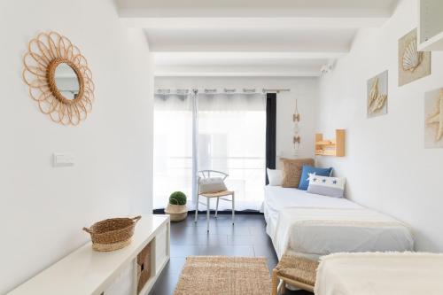 a white bedroom with two beds and a mirror at Casa del Mar in Tamariu