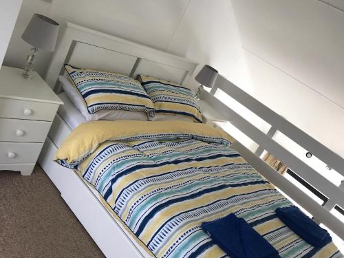 uma cama branca com almofadas listradas num quarto em Brighton Marina Floating home em Brighton & Hove