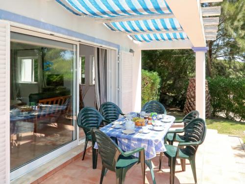 a dining table and chairs on a patio with a glass door at Holiday Home Monte Quercus by Interhome in Porches
