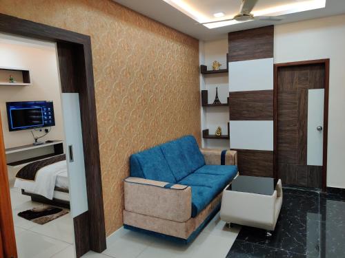uma sala de estar com uma cadeira azul e uma cama em Pagadala Grand Residency em Bāpatla