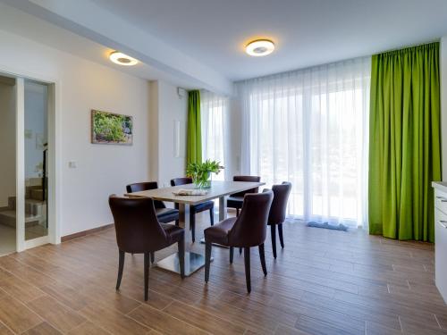 comedor con cortinas verdes, mesa y sillas en Apartment Ankerplatz by Interhome en Großpösna