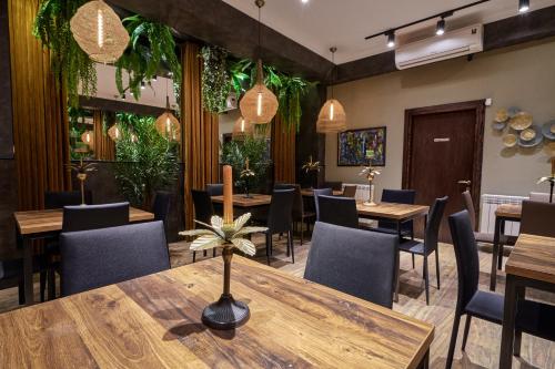 a restaurant with wooden tables and chairs and plants at Hotel City in Tbilisi City