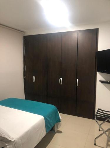 a bedroom with a bed and wooden cabinets at Apartamentos Amoblados- Buenavista Barranquilla in Barranquilla