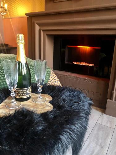 a bottle of champagne and two glasses on a table with a fireplace at Slapen bij Café de Concurrent in Vlissingen