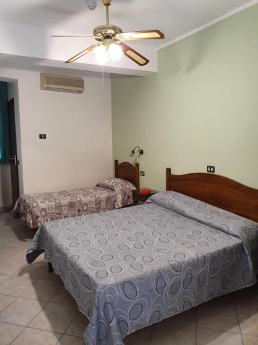 a bedroom with two beds and a ceiling fan at Hotel Caribe in Casalnuovo di Napoli