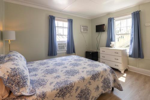 a bedroom with a bed and a dresser and windows at Blackbeard's Lodge in Ocracoke