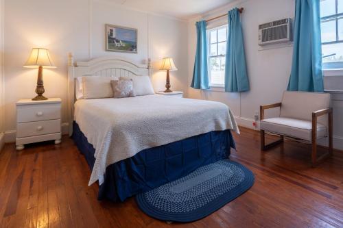 a bedroom with a bed and a chair and windows at Blackbeard's Lodge in Ocracoke