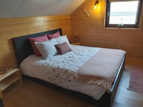 een slaapkamer met een bed met kussens en een raam bij Le refuge Ardennais in Libramont