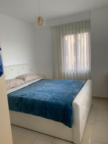 a bedroom with a bed with a blue blanket on it at Diar Apartment in Durrës