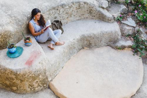 a woman sitting on a stone bench reading a book at Sol de Minca Eco Lodge in Minca