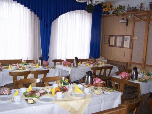 a dining room with white tables and chairs with food at Willa Jasna in Czorsztyn