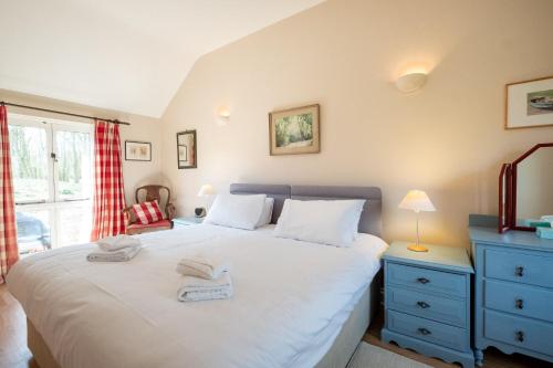 um quarto com uma grande cama branca e uma cómoda azul em The Stables, Theberton em Theberton