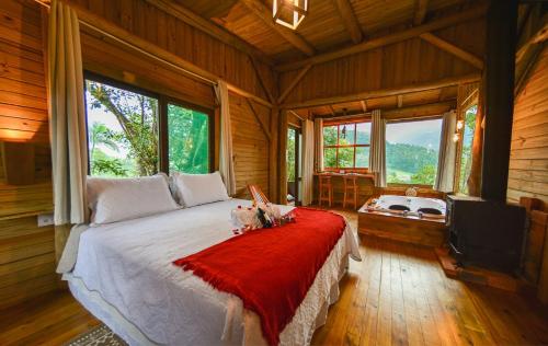 a bedroom with a large bed in a room with windows at Pousada Flor de Lótus dos Canyons in Praia Grande