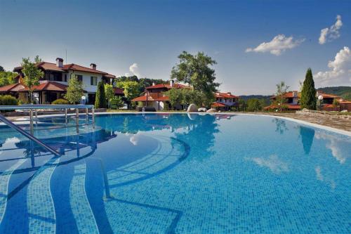 une grande piscine bleue avec des maisons en arrière-plan dans l'établissement Марковската къща, à Oreshak