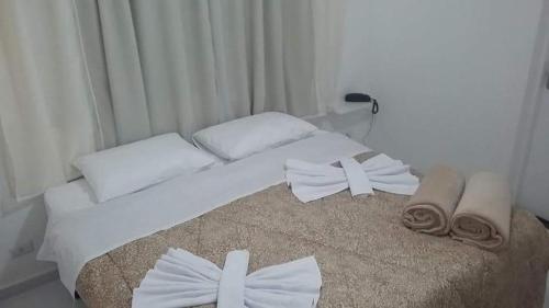 a white bed with white pillows and towels on it at Planalto Hotel Arujá in Arujá