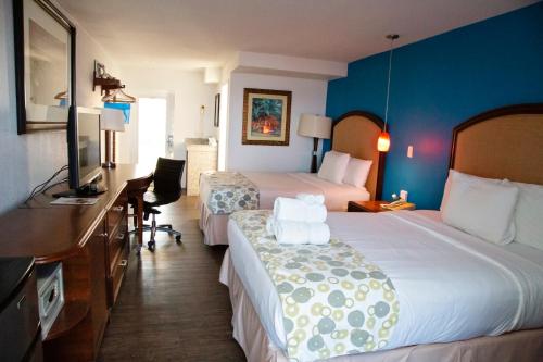 a hotel room with two beds and a desk at Daytona Dream Inn By AmeriVu in Daytona Beach