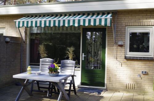 a patio with a table and chairs and a green door at Geschakelde bungalow op de Veluwe "De Eekhoorn" in Otterlo