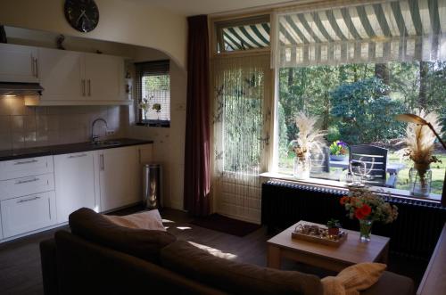 a living room with a couch and a large window at Geschakelde bungalow op de Veluwe "De Eekhoorn" in Otterlo