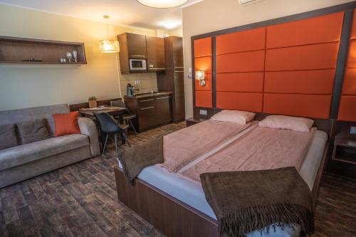 a bedroom with a large bed and a couch at 4 ÁSZ Deluxe Apartman in Gyula