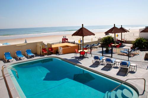 a swimming pool with the beach in the background at Daytona Dream Inn By AmeriVu in Daytona Beach