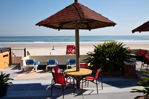 a table with chairs and an umbrella on the beach at Daytona Dream Inn By AmeriVu in Daytona Beach