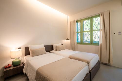 two beds in a white room with a window at La Memoria Hotel - City Centre in Ho Chi Minh City