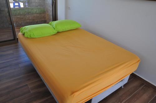 a bed with green pillows on it in a room at Vastu Dead Sea apartment in Arad