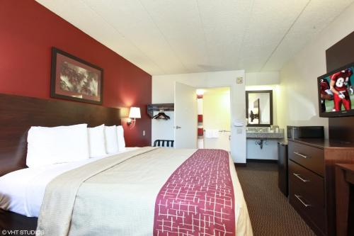 a hotel room with a large bed with red walls at Red Roof Inn Michigan City in Michigan City