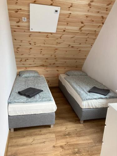 two beds in a room with wooden walls at Mega widok 3 in Szklarska Poręba