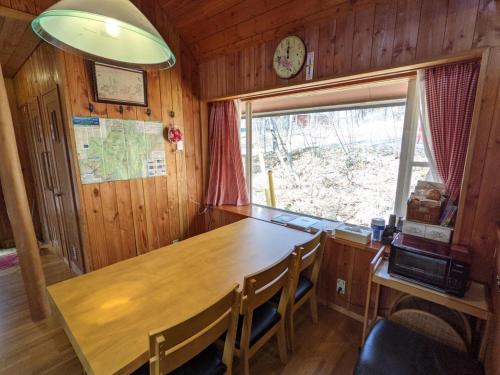 uma sala de jantar com uma mesa de madeira e uma janela em Asuka's House 八ヶ岳 em Hokuto