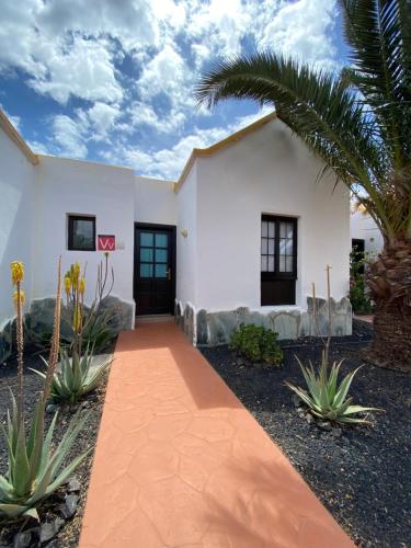 een wit huis met een palmboom en een loopbrug bij Apartment El Barco - Las Casas de Aron in Caleta De Fuste