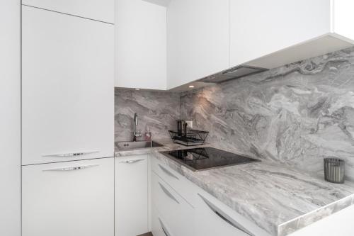 a kitchen with white cabinets and a marble wall at New Comfortable 2 Bedroom Cottage w/Big Terrace in Jūrmala