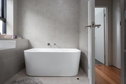 a white bath tub in a bathroom with a mirror at Stylish 2-Bed Apartment with BBQ Patio Near Beach in Sydney