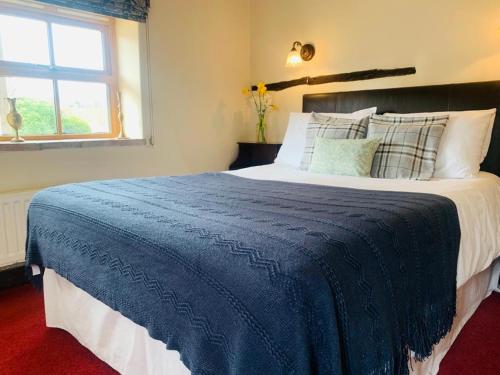 a bedroom with a large blue bed with a window at George & Dragon Country Pub & Hotel Wolverton Townsend in Tadley