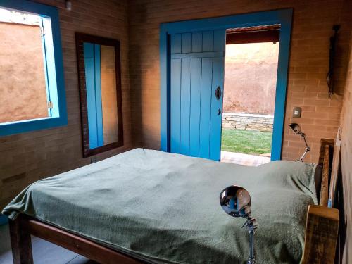 1 dormitorio con 1 cama con puerta azul y ventana en Casa Itamotinga, en Pirenópolis