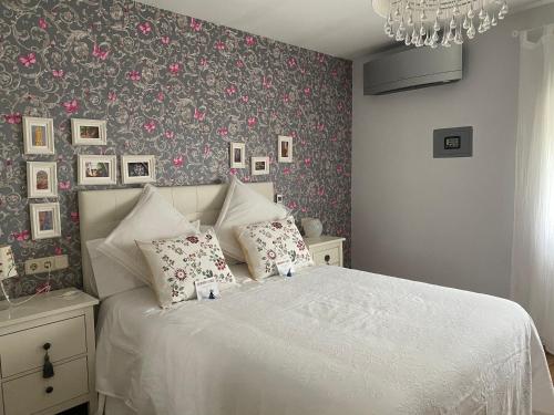 a bedroom with a white bed with floral wallpaper at Apartamento La Biblioteca en Cuenca in Cuenca