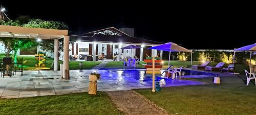 una casa con piscina di notte di Pousada e Restaurante Lual do Parajuru a Parajuru