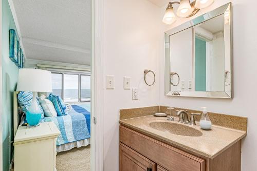 baño con lavabo y cama con espejo en Pelican Beach, en Ocean City