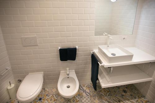 a white bathroom with a toilet and a sink at DilettaAnna Luxury apartment Lipari in Tropea