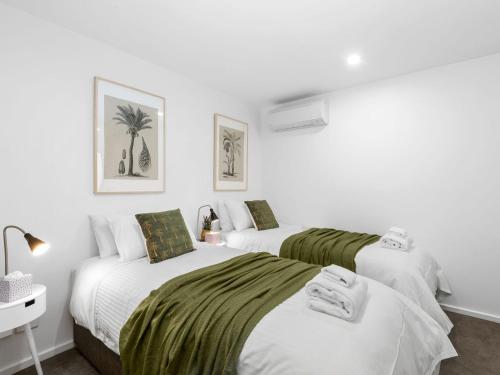 two beds in a room with white walls at Oceania 3 in Lorne