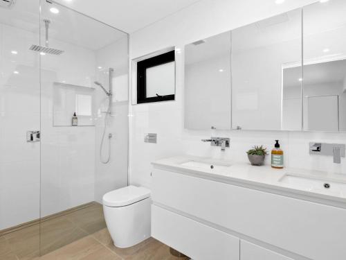 a white bathroom with a toilet and a sink at Oceania 3 in Lorne
