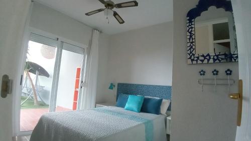 a bedroom with a bed with blue pillows and a ceiling fan at Apartamento Pardela in Adeje