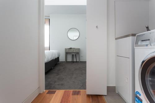 a laundry room with a bed and a washer and dryer at Stylish 2-Bed Apartment with BBQ Patio Near Beach in Sydney