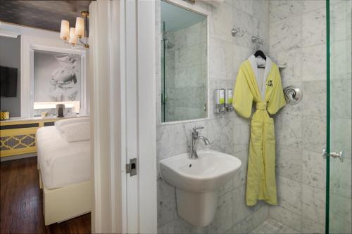 波士頓的住宿－Staypineapple, A Delightful Hotel, South End，浴室设有水槽,墙上有黄色的浴袍。