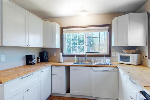 a kitchen with white cabinets and a sink and a window at Sweet Netarts in Tillamook
