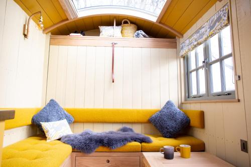 a room with a yellow couch and a window at Little Plovers Shepherd Hut in Chichester