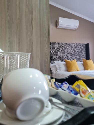 a room with a table with dishes and a bed at Village Kulture - Guest House in Rustenburg