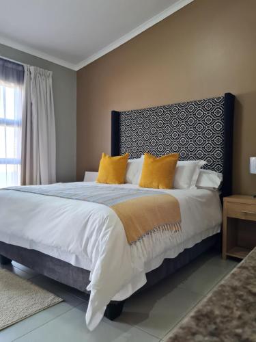 1 dormitorio con 1 cama grande con almohadas amarillas en Village Kulture - Guest House en Rustenburg