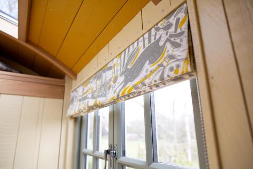 a window with a curtain in a room with at Little Plovers Shepherd Hut in Chichester