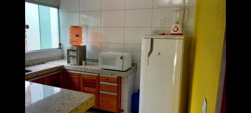 uma cozinha com um frigorífico branco e um micro-ondas em Casa dos coqueiros em Pirenópolis